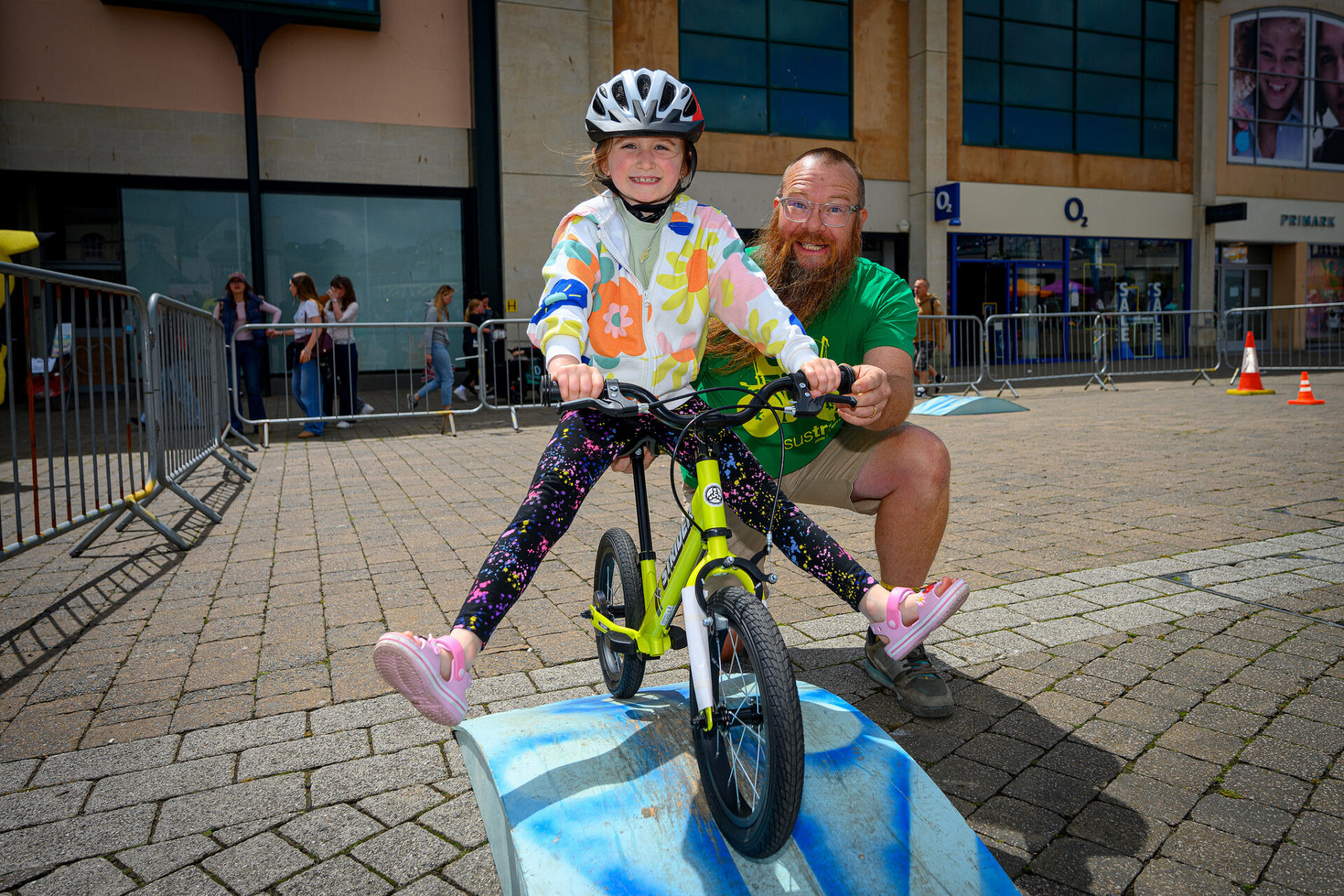 Child on a bicycle with an adult helping during Truro Children's Day